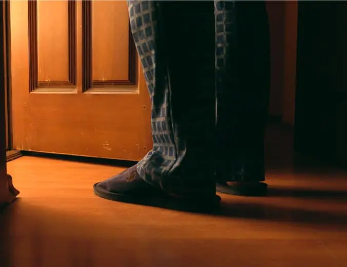 man taking a trip to the bathroom in the middle of the night in slippers and pajamas